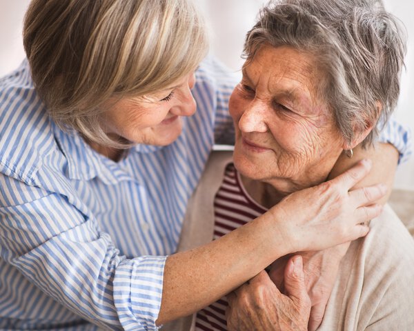 Zwei ältere Damen umarmen sich und lachen sich an | © Halfpoint - stock.adobe.com